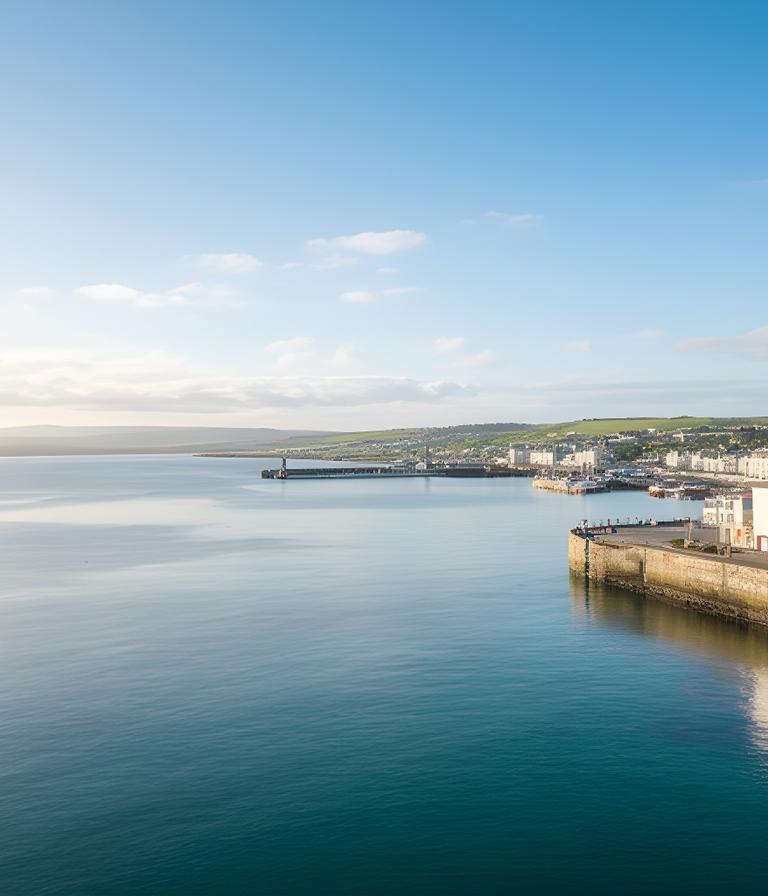 The Dún Laoghaire waterfront near West Pier on a clear day, with calm water and a bright harbour view
