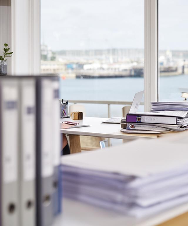 Principal solicitor in a modern West Pier office with legal files and a harbour view in the background
